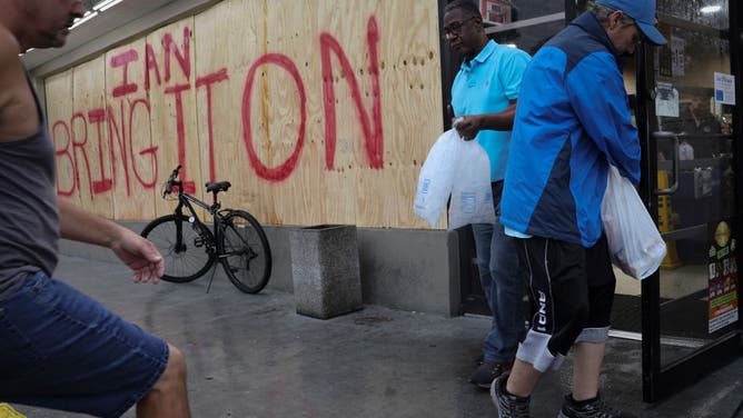 Patrons exit a convenience store while collecting last minute supplies in advance of the arrival of Hurricane Ian on September 28, 2022 in Tampa, Florida. Ian is expected to make landfall later today on the Gulf Coast of the state. (Photo by Win McNamee/Getty Images)