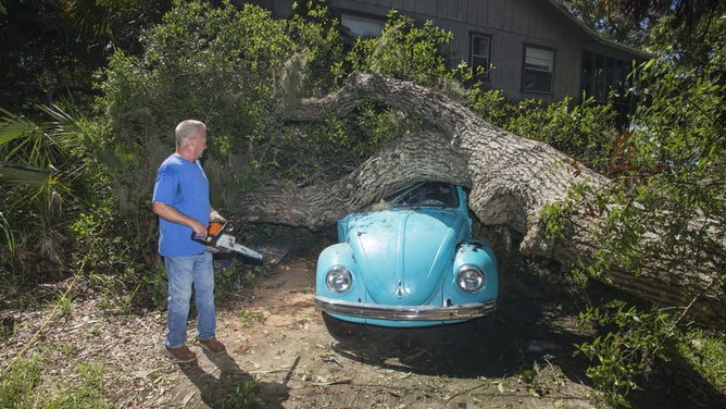 Tom Reams looks over a tree on top of his 15 year old daughter's Volkswagen Beetle and house cause by the wind and storm surge from Hurricane Hermine at Alligator Point, Florida September 2, 2016.