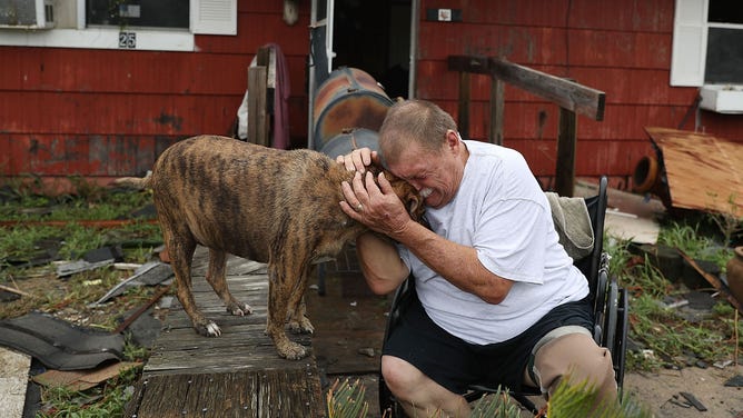 Steve Culver cries with his dog Otis as he talks about what he said was the, "most terrifying event in his life," when Hurricane Harvey blew in and destroyed most of his home while he and his wife took shelter there on August 26, 2017 in Rockport, Texas.