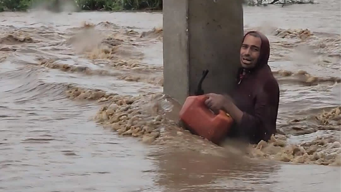 A man is seen clinging to a cement pole to prevent being swept away by raging floodwaters in Puerto Rico during Hurricane Fiona.