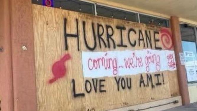 The phrases "HURRICANE coming...we're going," "stay safe" and "LOVE YOU A.M.I.!" are spray painted onto boarded up windows in Anna Maria Island in Manatee County, Florida. "A.M.I." stands for Anna Maria Island.