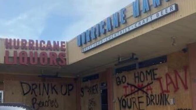 The words "GO HOME IAN YOU'RE DRUNK" are spray painted onto the boarded up windows of a restaurant in Manatee County, Florida.