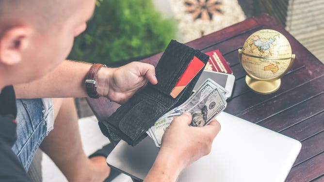 A man looks at the contents of his wallet.