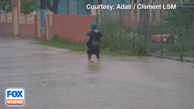 A woman wading though floodwater