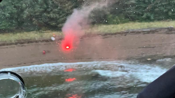 A man signals a Coast Guard aircrew with a flare after his vessel capsized in Freshwater Bay, Alaska, Oct. 19, 2022. At approximately 5 a.m., Coast Guard Sector Juneau Command Center watchstanders overheard a mayday call from the vessel and coordinated rescue assets to the scene of the incident.