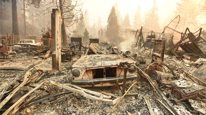 TOPSHOT - The burned remains of a vehicle and home are seen during the Camp fire in Paradise, California on November 8, 2018. - More than one hundred homes, a hospital, a Safeway store and scores of other structures have burned in the area and the fire shows no signs of slowing. (Photo by Josh Edelson / AFP) (Photo credit should read JOSH EDELSON/AFP via Getty Images)