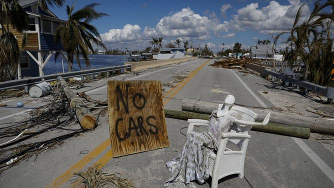 A "No Cars" signs on the damaged Pine Island Road following Hurricane Ian in Matlacha Isles, Florida, US, on Saturday, Oct. 1, 2022. Research firm Enki Holdings LLC pegs the economic cost of Hurricane Ian at $60 billion to $70 billion, based on damage to homes and infrastructure, as well as the cost of reconstruction and longer-term knock-on effects including the disruption in tourism. 