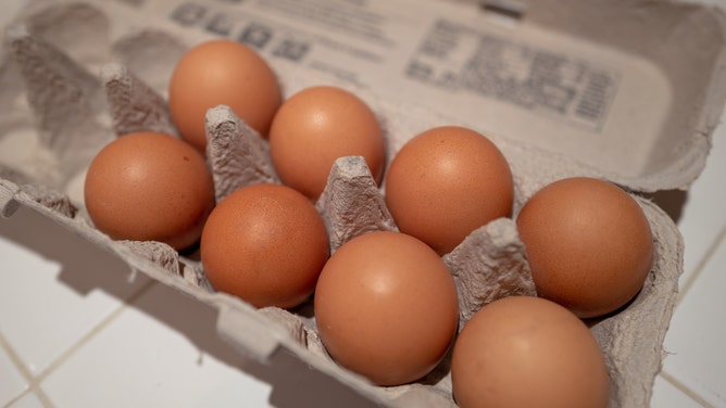 Close-up shot of eight eggs in an egg carton sitting on a kitchen counter.