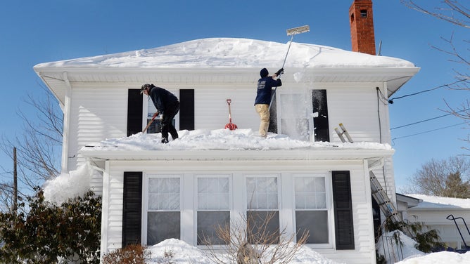 Larry Goodno, left, and Lewis Jarrett clear snow from the roof of a house on Brighton Ave on Wednesday February 11, 2015.  in Portland.