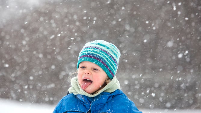 A girl tries to catch snowflakes on her tongue.