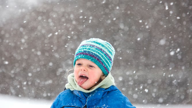 A girl tries to catch snowflakes with her tongue.