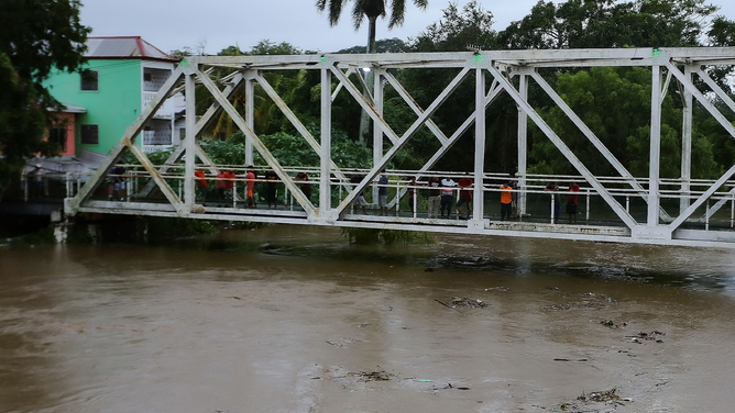 Residents look at the Chamelecon river that threatens to overflow in the municipality of La Lima, department of Cortes, Honduras, due to the rains left by Tropical Storm Julia on October 9, 2022. - Julia was expected to emerge off the Pacific coast by Sunday evening, then "move very near to and parallel to the Pacific coasts of Honduras, El Salvador and Guatemala tonight and Monday", the US National Hurricane Center said in its latest advisory.