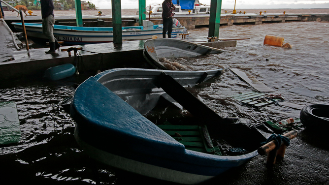 Fishermen look at their sunken boats after Hurricane Julia hit the town of Bluefields on Nicaragua's Caribbean coast on October 9, 2022. - Hurricane Julia raked across Nicaragua Sunday, lashing the country with winds and heavy rain and bringing potentially life-threatening flash flooding and mudslides to much of Central America.