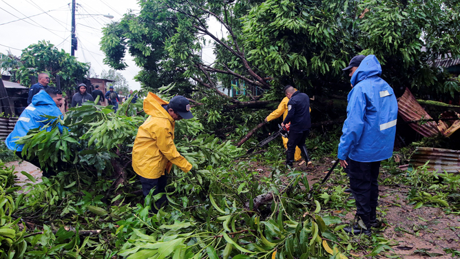 Nicaragua's National Police members try to prune fallen trees following the passage of Hurricane Julia in the town of Bluefields, on the Caribbean coast of Nicaragua on October 9, 2022. - Hurricane Julia raked across Nicaragua Sunday, lashing the country with winds and heavy rain and bringing potentially life-threatening flash flooding and mudslides to much of Central America.