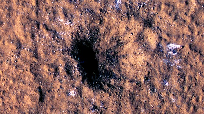 HiRISE Views a Mars Impact Crater Surrounded by Water Ice: Boulder-size blocks of water ice can be seen around the rim of an impact crater on Mars, as viewed by the High-Resolution Imaging Science Experiment (HiRISE camera) aboard NASA’s Mars Reconnaissance Orbiter. The crater was formed Dec. 24, 2021, by a meteoroid strike in the Amazonis Planitia region.