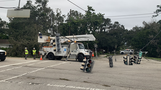 Utility crews are seen examining downed power lines and traffic signals in Sarasota, Florida.