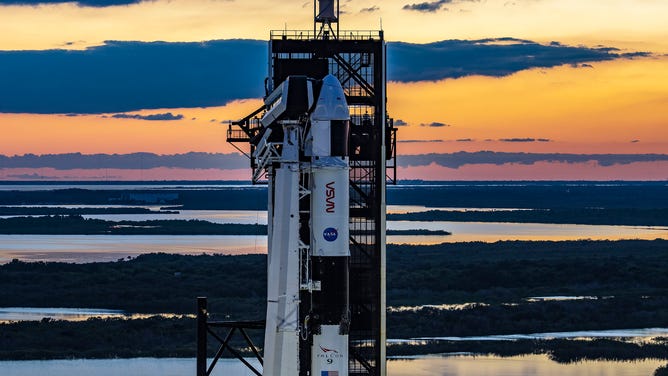 The sun sets behind a SpaceX Falcon 9 rocket and Dragon spacecraft at Kennedy Space Center in Florida ahead of the Crew-5 astronaut launch.