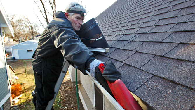 FILE - A professional gutter cleaner cleans gutters ahead of a winter storm.