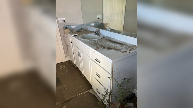 The bathroom counter and floor tiles covered in sand and muck.
