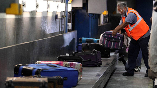 FILE - An airport worker is seen loading luggage.