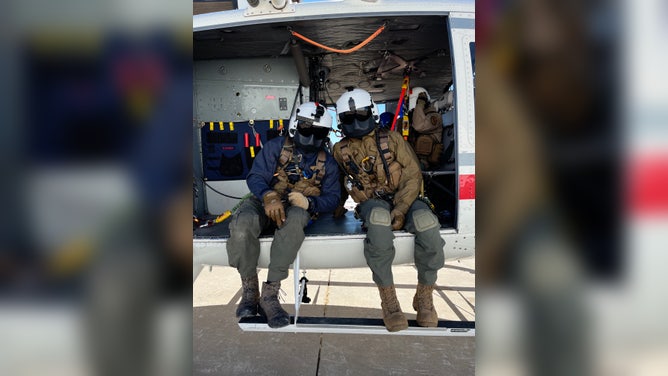 Crew members sitting in a helicopter.