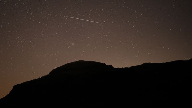 A meteor shoots across the night sky.