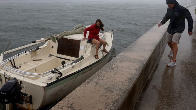 Kelly McFadden (L) and Kyle McFadden help tie up a sailboat next to the seawall after it broke away from its anchor due to the high winds and surf from the approaching Tropical Storm Nicole on November 09, 2022 in West Palm Beach, Florida.
