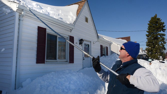 A man works to remove snow from the roof in Buffalo, New York.
