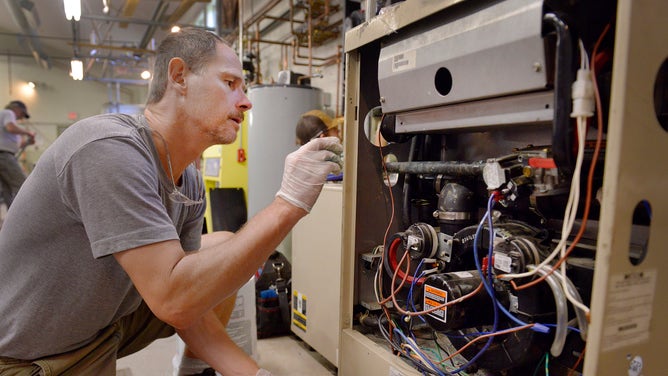 A man works on a gas furnace.