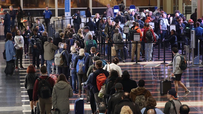 FILE - Travelers wait in line to go through the security area at Reagan National Airport on November 21, 2017, in Arlington, Virginia.