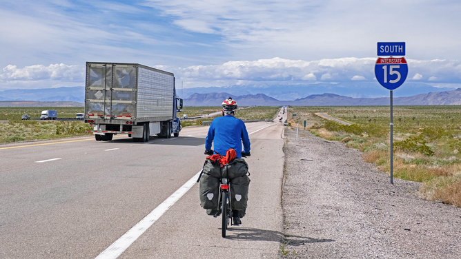FILE - Solitary touring cyclist cycling along the Interstate 15/I-15 through Mohave County in Arizona and heading for Las Vegas, United States, USA.
