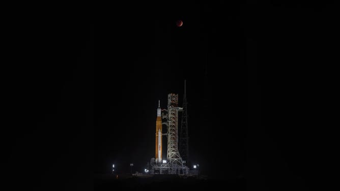 A total lunar eclipse glows above NASA's Space Launch System rocket and Orion spacecraft at Kennedy Space Center Pad 39B in the pre-dawn hours on Nov. 8, 2022.