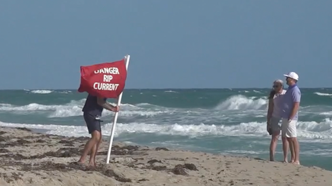A lifeguard sets up a flag warning beachgoers of rip currents in Palm Beach, Florida.