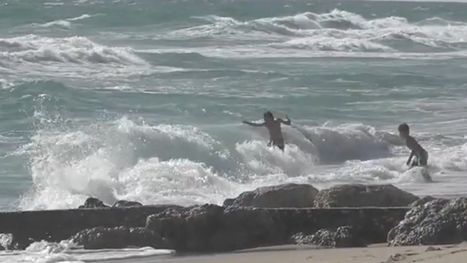 Beachgoers enjoy the choppy waves in Palm Beach, Florida.