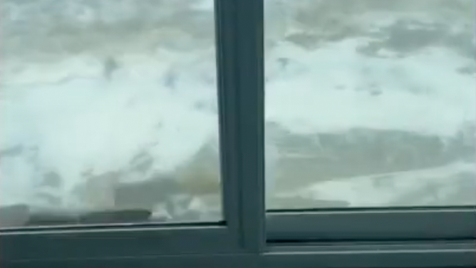 The ocean draws near in this view out of sliding glass doors.