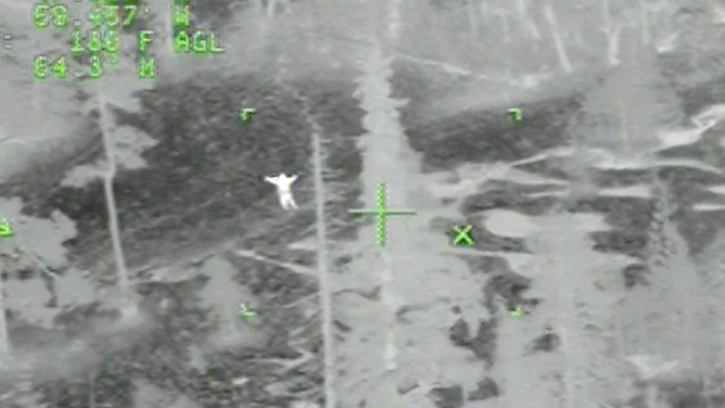 Irving Langmaid stands with his arms raised to catch the attention of the U.S. Coast Guard helicopter crew.