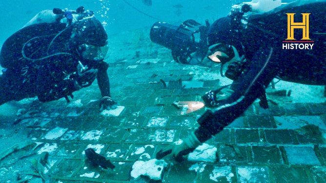Divers with The History Channel examine a piece of the Space Shuttle Challenger. 