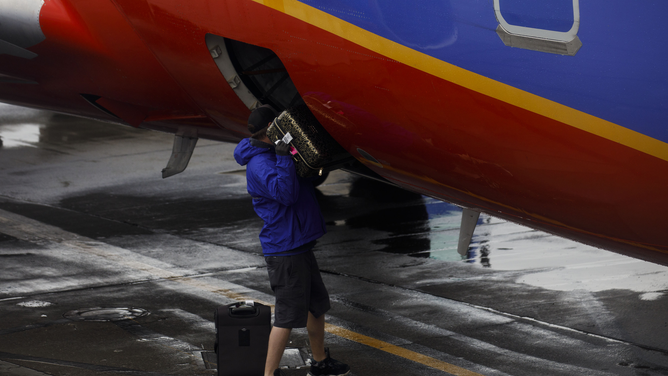 FILE - A ground crew member loads baggage onto a Southwest Airlines Co. Boeing Co. 737-700 aircraft on the tarmac at San Francisco International Airport (SFO) in San Francisco, California, U.S., on Wednesday, March 27, 2019.