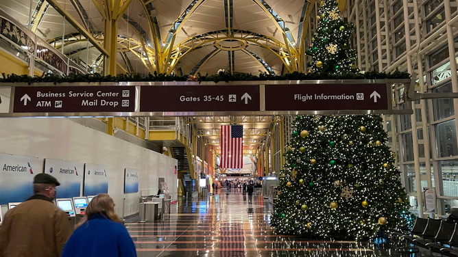 FILE - People walk near a Christmas tree inside the Washington Reagan National Airport (DCA) on December 18, 2020 in Arlington, Virginia.