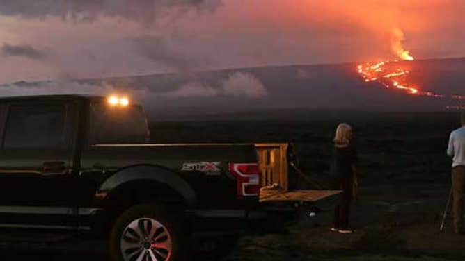 People stand on the side of the road to photograph the eruption of the Mauna Loa volcano on December 04, 2022 near Hilo, Hawaii.