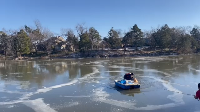 The firefighter successfully hoists the dog out of the water.