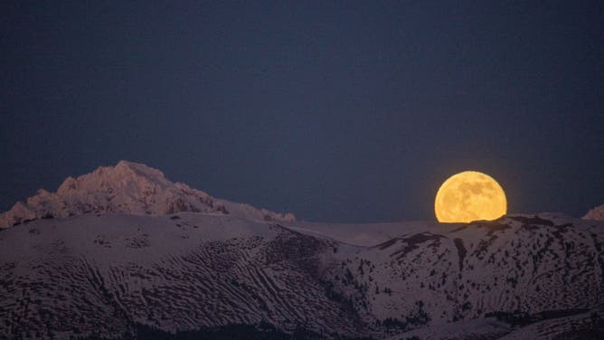 The Cold Moon rises at sunset behind Monte Prena Mountain in Gran Sasso National Park in Italy, on December 19, 2021. The Cold Moon is the last full moon of the year.