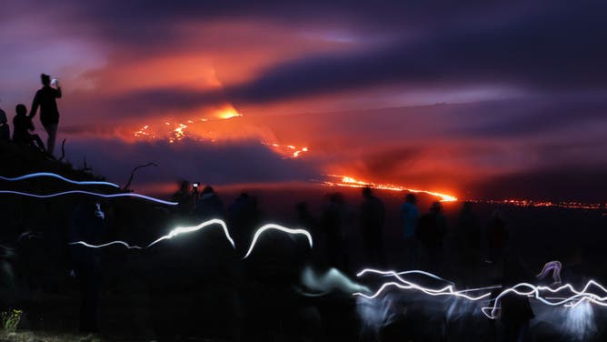 People gather on top of a hill to watch Mauna Loa erupts, the world's largest active volcano on December 1, 2022 in Big Island of Hawaii, United States.