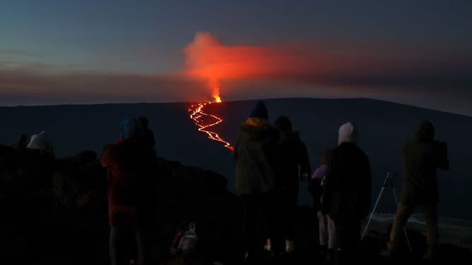 A family from town of Kona are gathered and pray on the top of Mauna Kea mountain as they watch Mauna Loa erupts, the world's largest active volcano on December 3, 2022 in Big Island of Hawaii, United States.