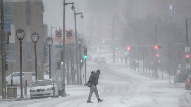 People travel in downtown Milwaukee as Wisconsin prepares for a winter storm that could bring blizzard conditions in the coming days, causing possible power outages and making holiday travel conditions hazardous.