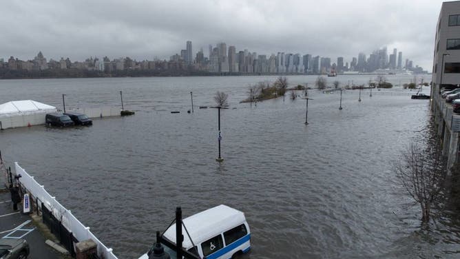 Storm clouds are seen as the Hudson River spills over a river wall in front of the skyline of lower Manhattan in New York City during an severe flooding due to the winter storm in New Jersey, United States on December 23, 2022.
