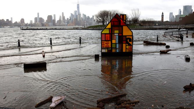 The Hudson River spills over a river wall in front of the skyline of lower Manhattan in New York City during an extreme high tide on December 23, 2022, in Hoboken, New Jersey.