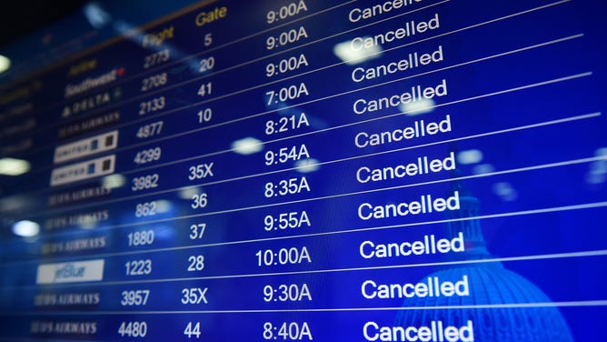 FILE - A screen of departing flights shows mass cancellations at Ronald Reagan Washington National Airport on Thursday March 05, 2015 in Arlington, VA.