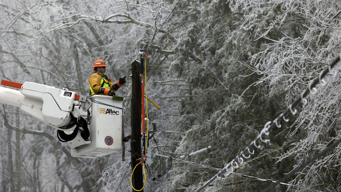 FILE - A worker fixes power lines following a winter storm near High Falls, New York, U.S., on Monday, Feb. 7, 2022.
