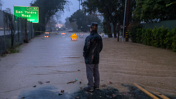 MONTECITO, CA-JANUARY 9, 2023: Lifelong Montecito resident George Quirin, 63, looks on towards a flooded Jameson Lane in Montecito, a result of San Ysidro creek overflowing due to heavy rainfall in the area.